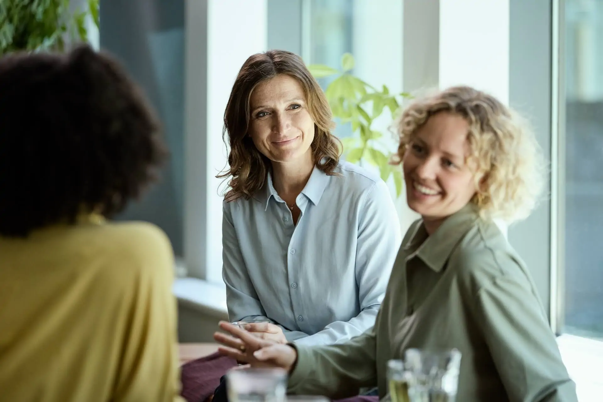 Drei Frauen sitzen im Büro und lachen