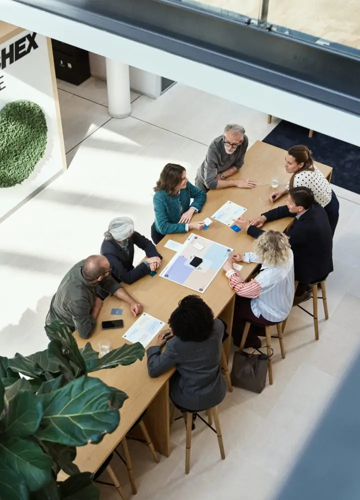 Acht Personen sitzen an einem großen Tisch in der Bürohalle