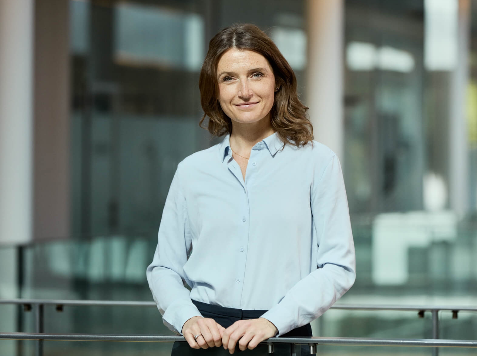 woman standing on an office bridge smiling