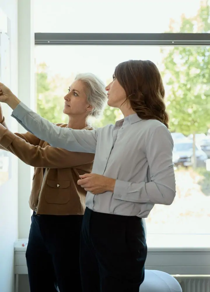 women standing at a white board